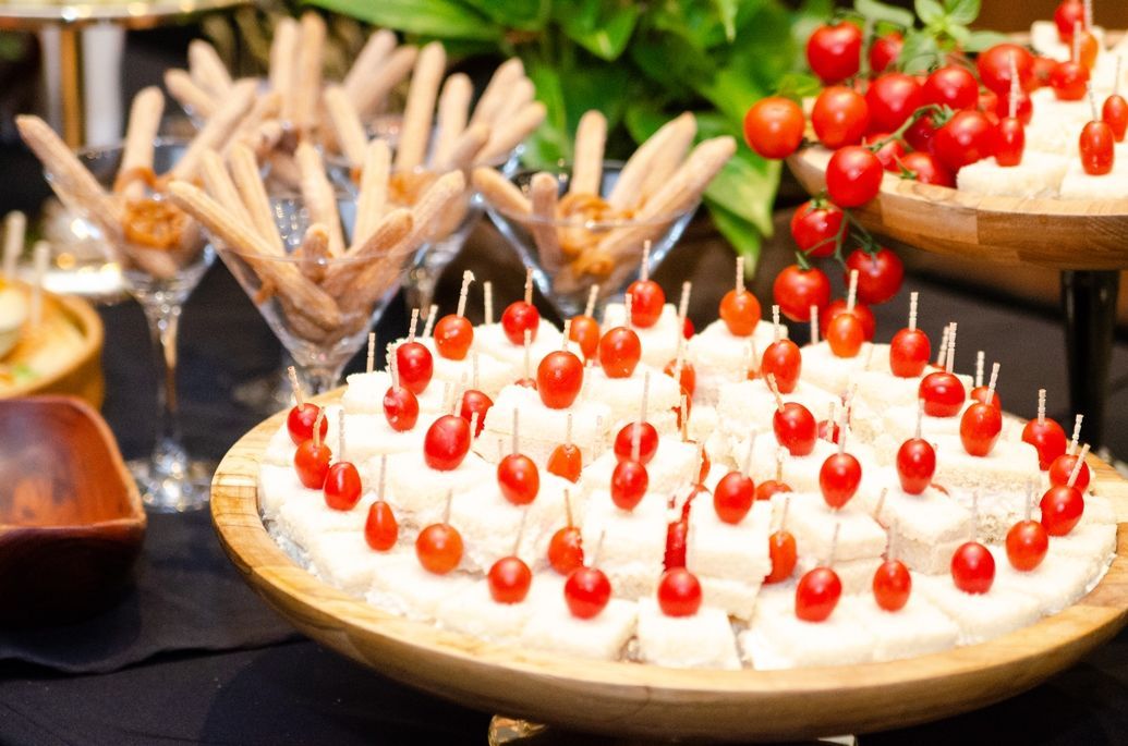 Um prato de madeira coberto com queijo e tomates sobre uma mesa.