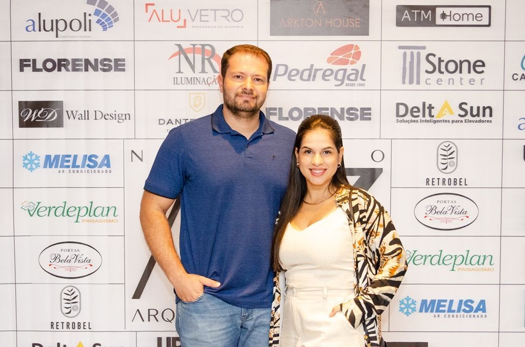 Um homem e uma mulher estão posando para uma foto em frente a uma parede de logotipos.