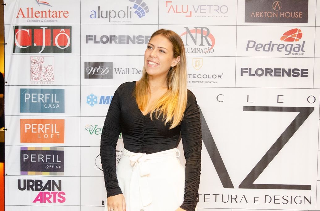 Uma mulher está parada em frente a uma parede com logotipos.