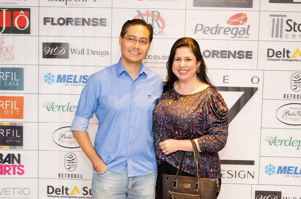 Um homem e uma mulher estão posando para uma foto em frente a uma parede de logotipos.