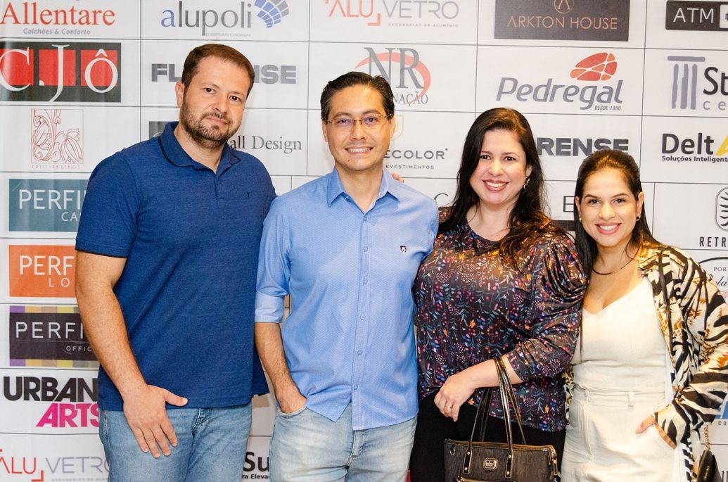 Um grupo de pessoas posando para uma foto em frente a uma parede com logotipos de diferentes empresas