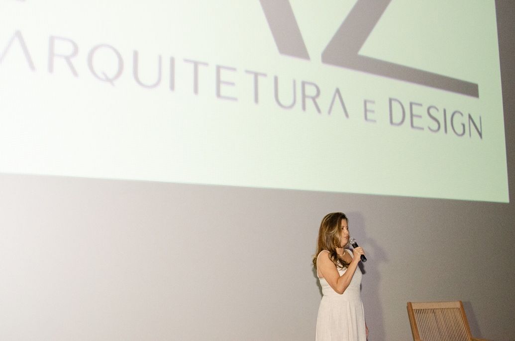 Uma mulher está em frente a uma tela de projeção que diz arquitetura e design