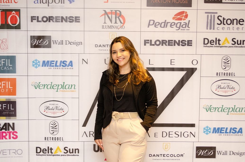 Uma mulher está parada em frente a uma parede com logotipos