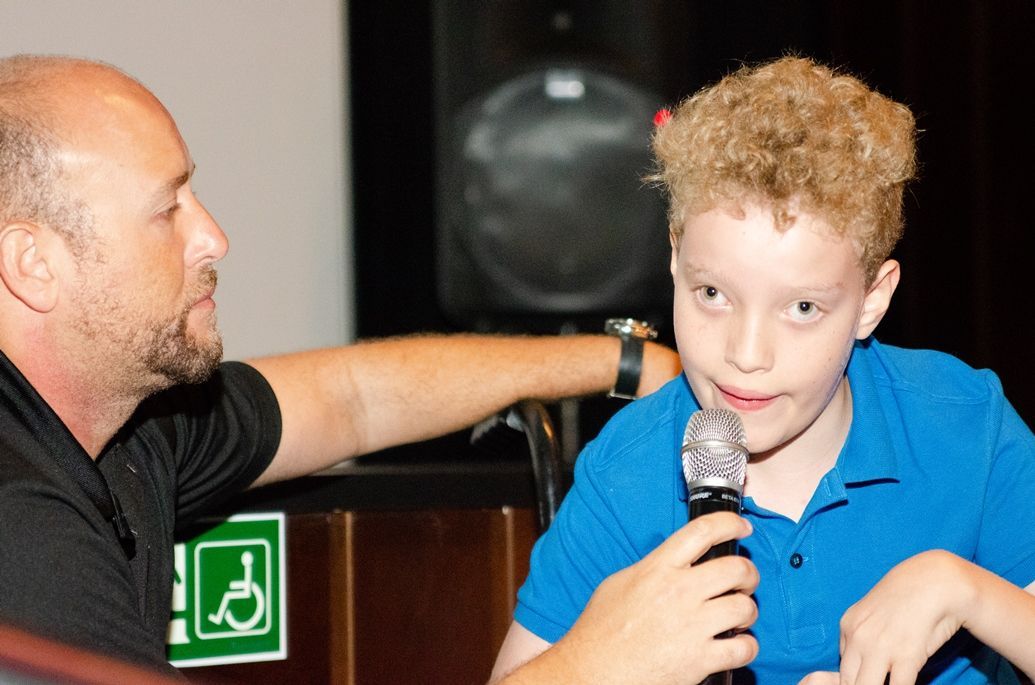Um homem está conversando com um menino que está segurando um microfone
