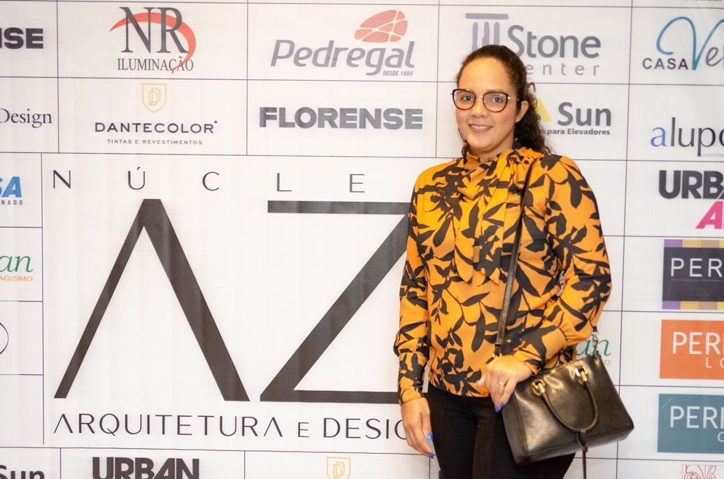 Uma mulher de camisa amarela está parada em frente a uma placa que diz az