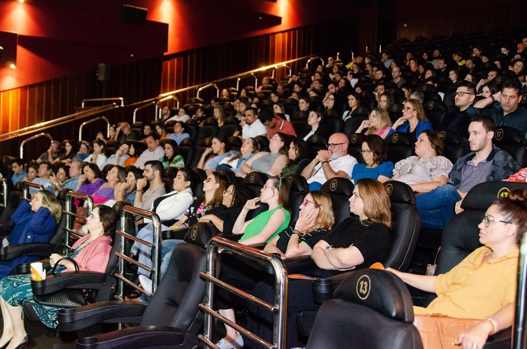 Um grande grupo de pessoas está sentado em um cinema assistindo a um filme.