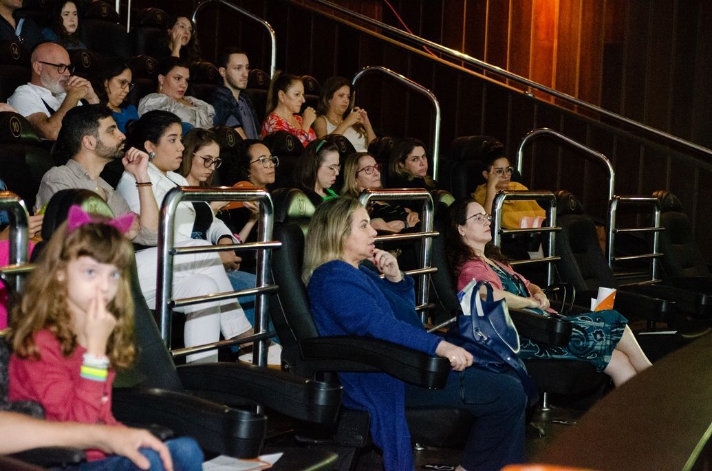 Um grupo de pessoas está sentado em um cinema assistindo a um filme.