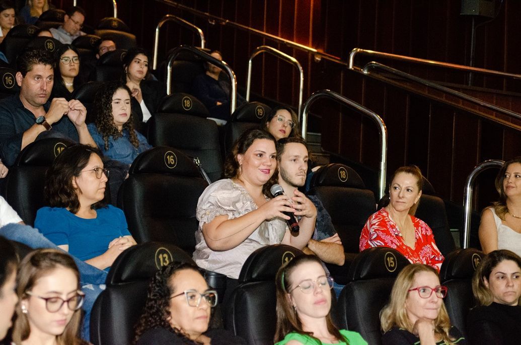 Um grupo de pessoas está sentado em um cinema assistindo a um filme.