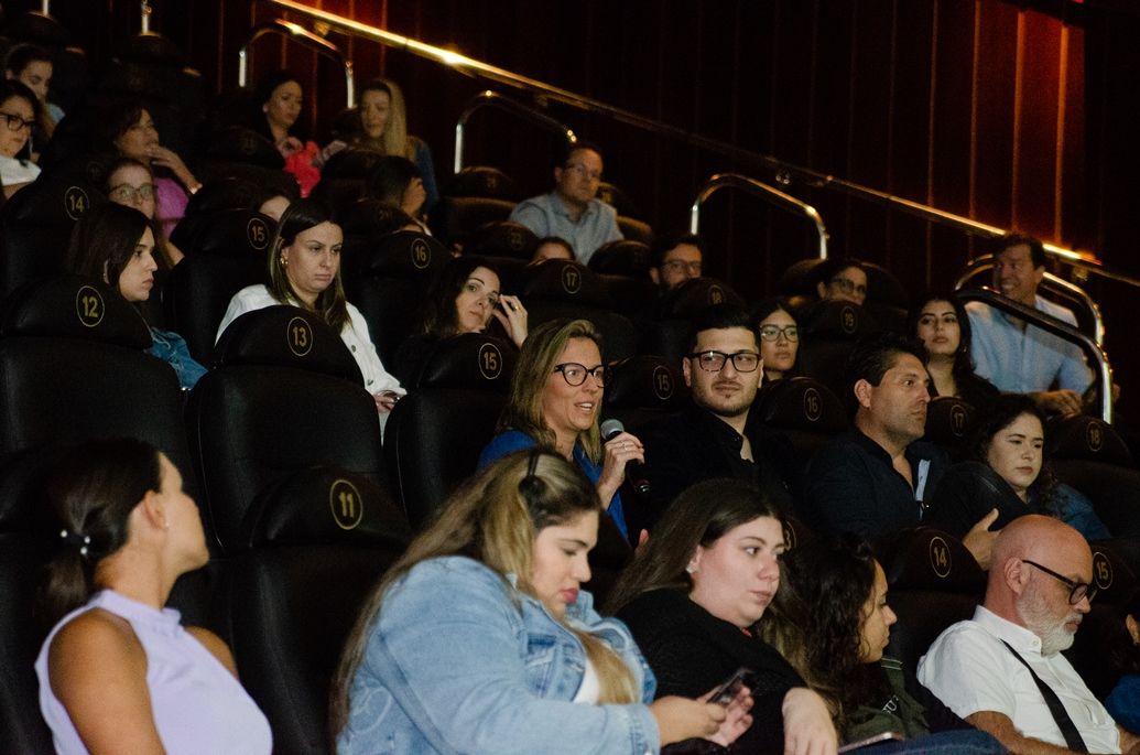 Um grupo de pessoas está sentado em um cinema assistindo a um filme.