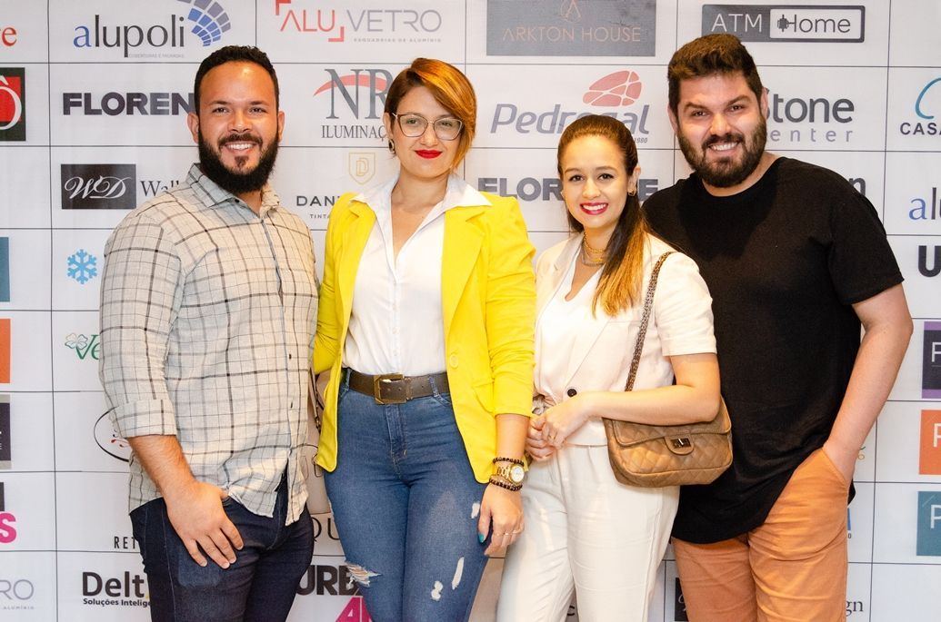 Um grupo de pessoas está posando para uma foto em frente a uma parede com logotipos.