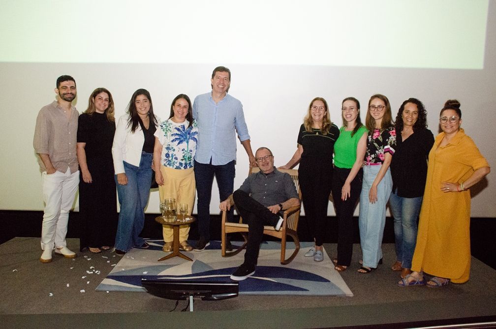 Um grupo de pessoas está posando para uma foto com um homem sentado em uma cadeira de balanço.