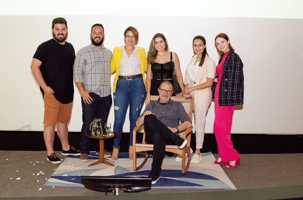 Um grupo de pessoas em pé ao redor de um homem em uma cadeira de balanço.