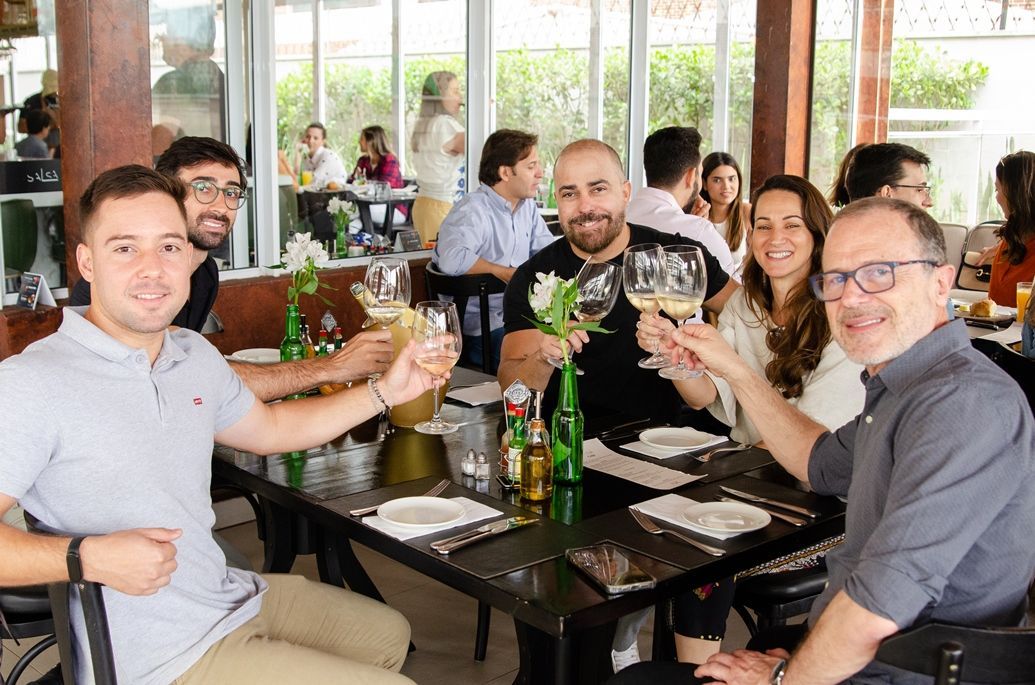 Um grupo de pessoas está sentado à mesa em um restaurante brindando com taças de vinho.