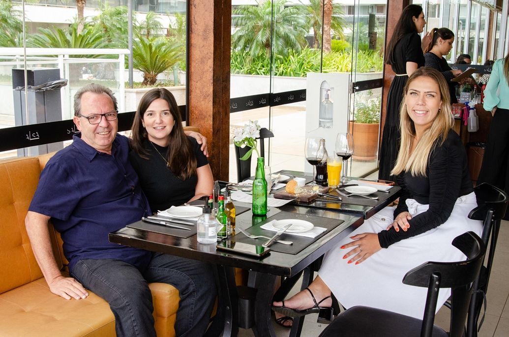 Um homem e duas mulheres estão sentados à mesa em um restaurante.