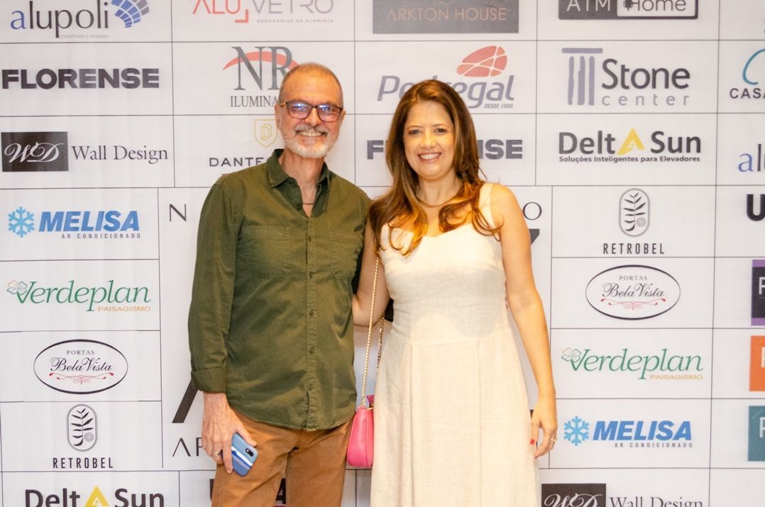 Um homem e uma mulher estão posando para uma foto em frente a uma parede de logotipos.
