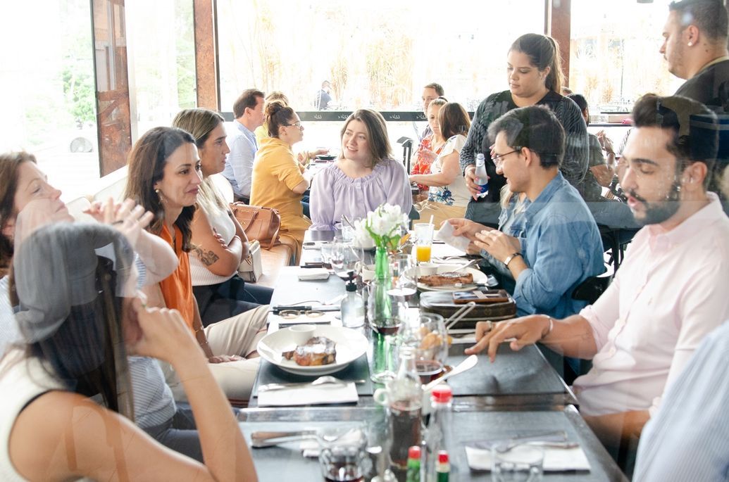 Um grupo de pessoas está sentado em uma mesa longa em um restaurante.