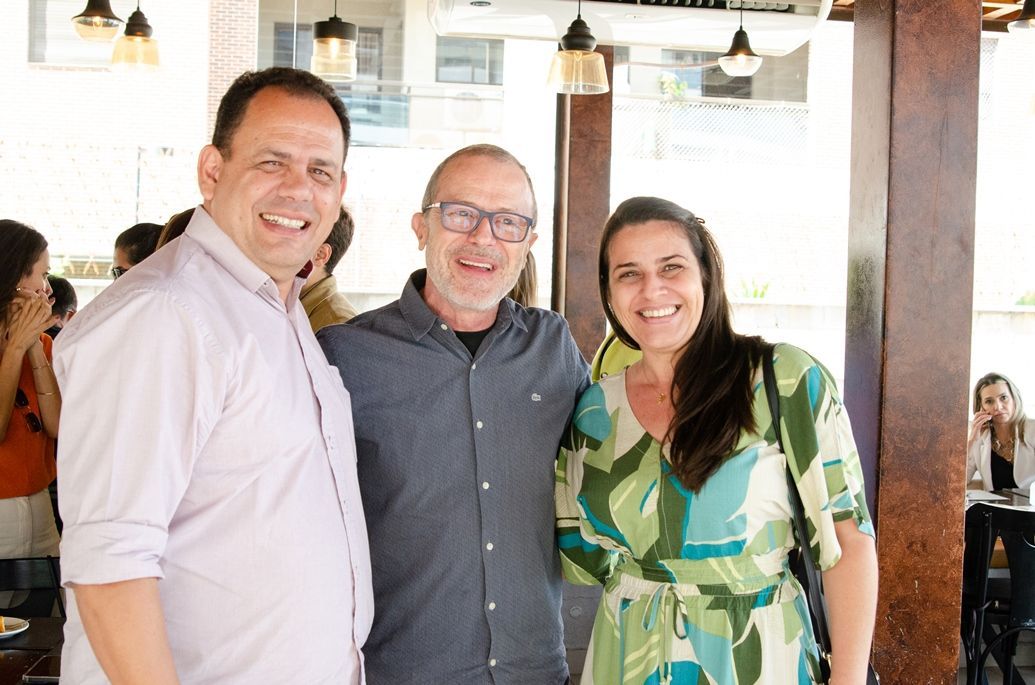 Três pessoas estão posando para uma foto em um restaurante.