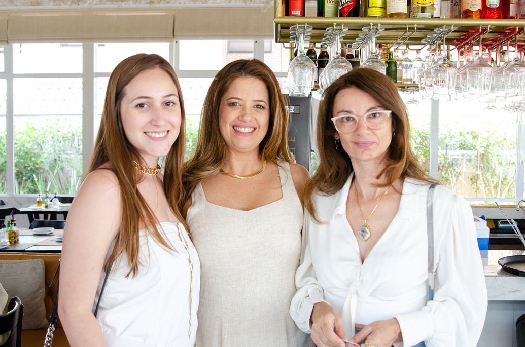 Três mulheres estão posando para uma foto em um restaurante.