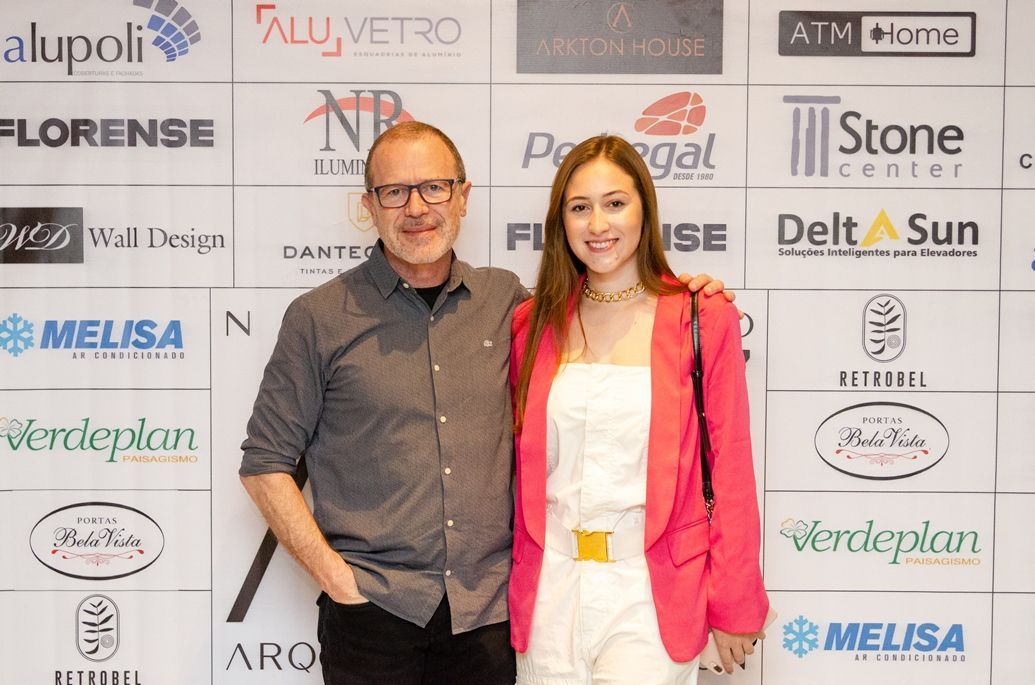 Um homem e uma mulher estão posando para uma foto em frente a uma parede com logotipos.