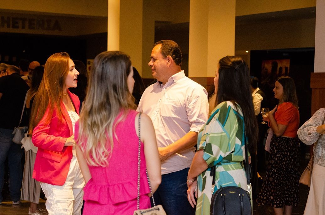 Um grupo de pessoas está em uma sala conversando entre si.