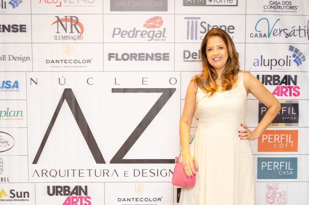 Uma mulher de vestido branco está em frente a um sinal de az
