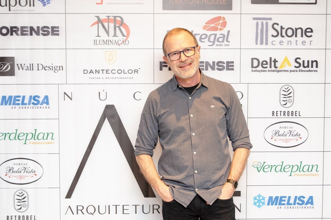 Um homem está parado em frente a uma parede com logotipos nela.