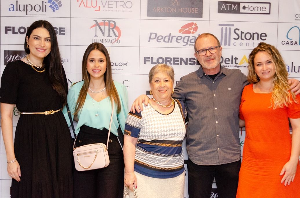 Um grupo de pessoas posando para uma foto em frente a uma parede com logotipos.