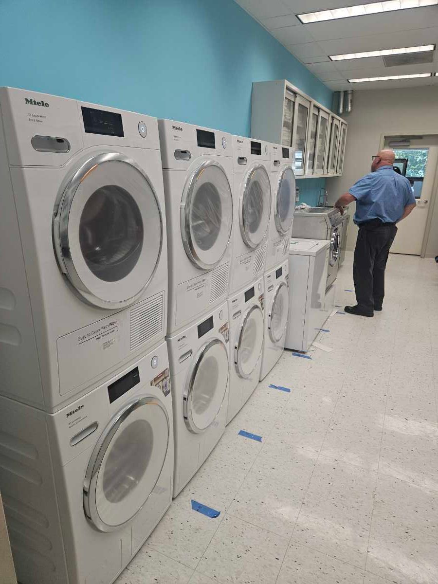 Laundry room with washing machines, open washer door, laundry basket, and detergents.
