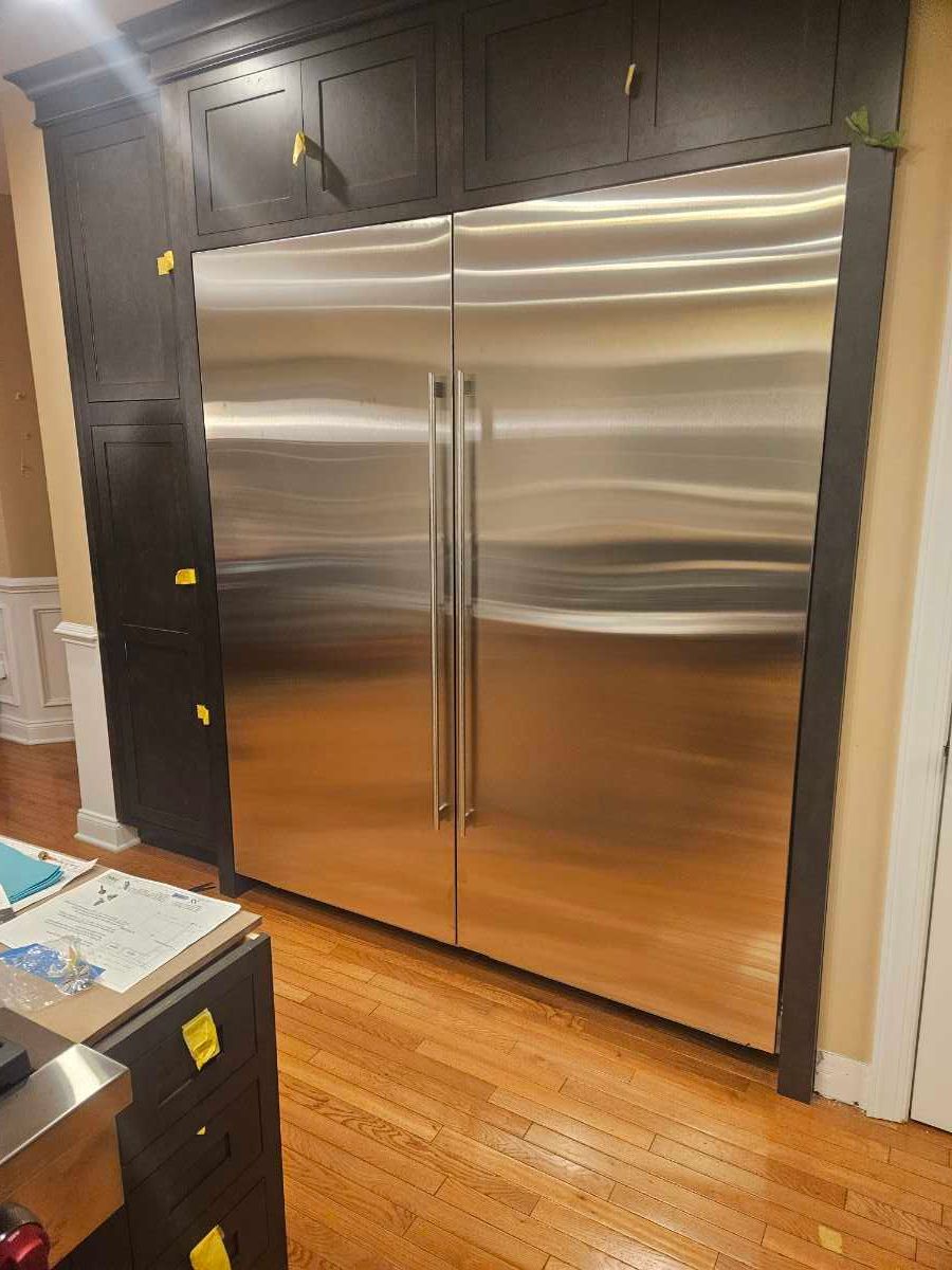 Modern kitchen with stainless steel appliances, central island, and wood flooring.