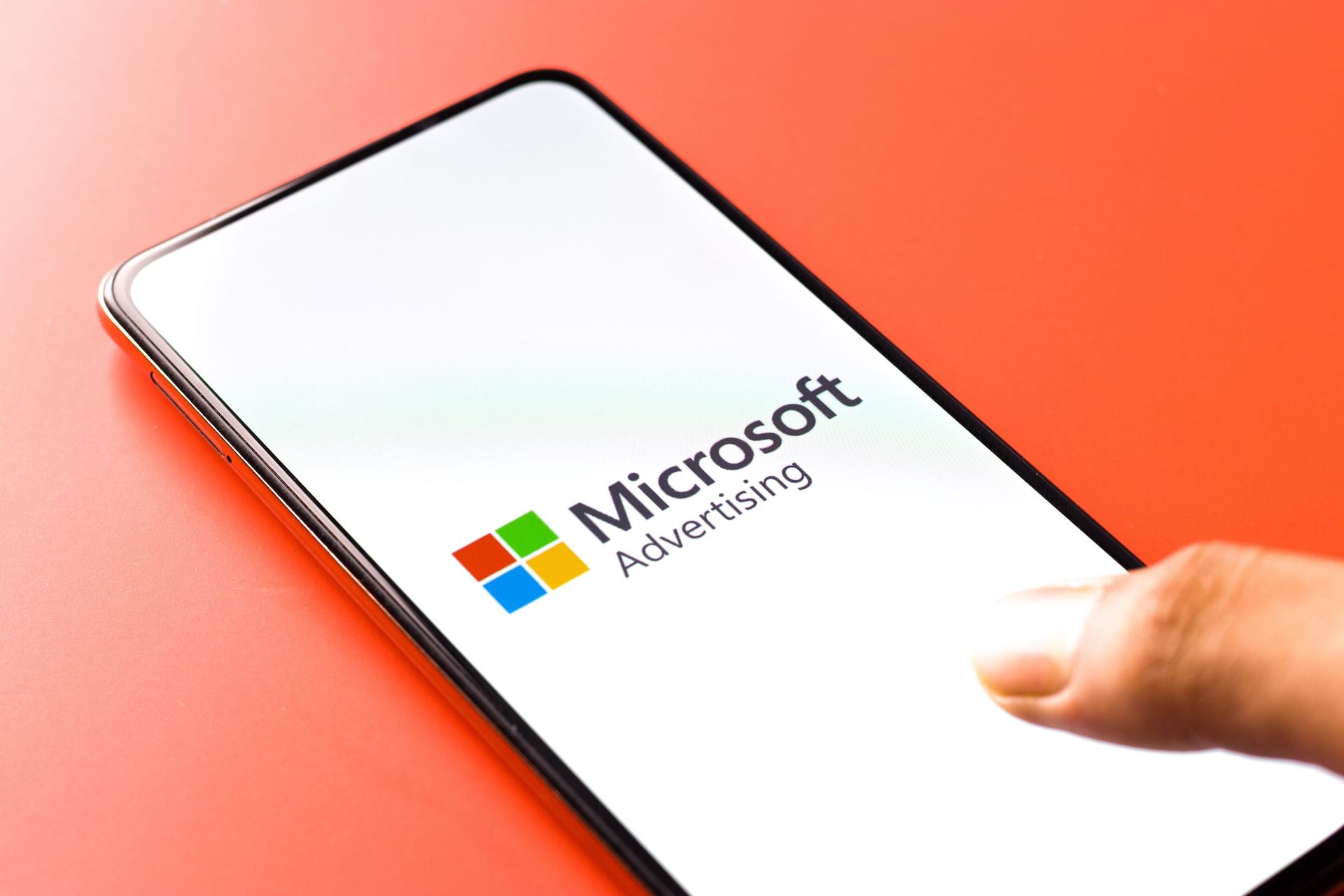 A person is holding a cell phone with the microsoft advertising logo on the screen.