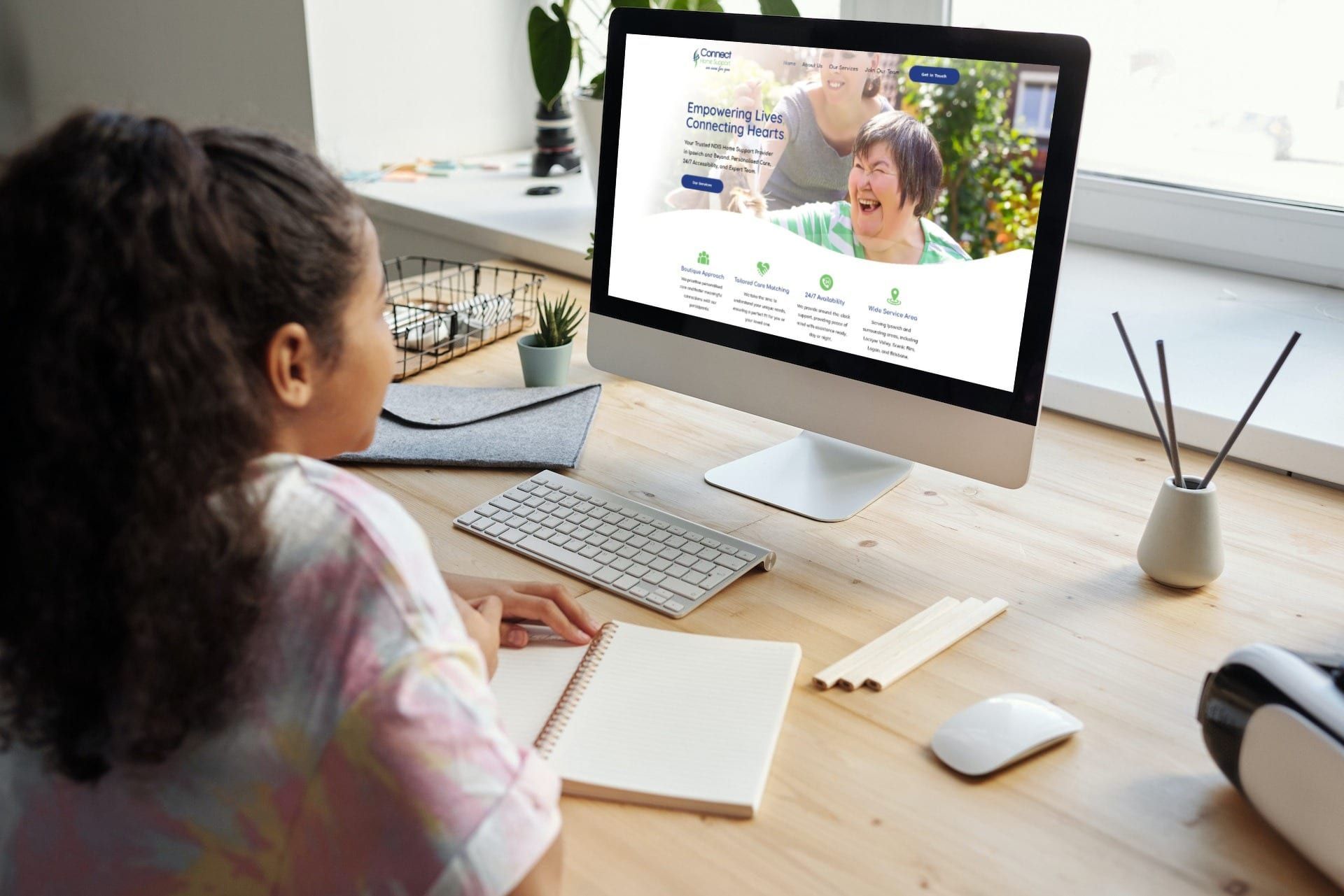 a girl is sitting at a desk looking at a computer screen .