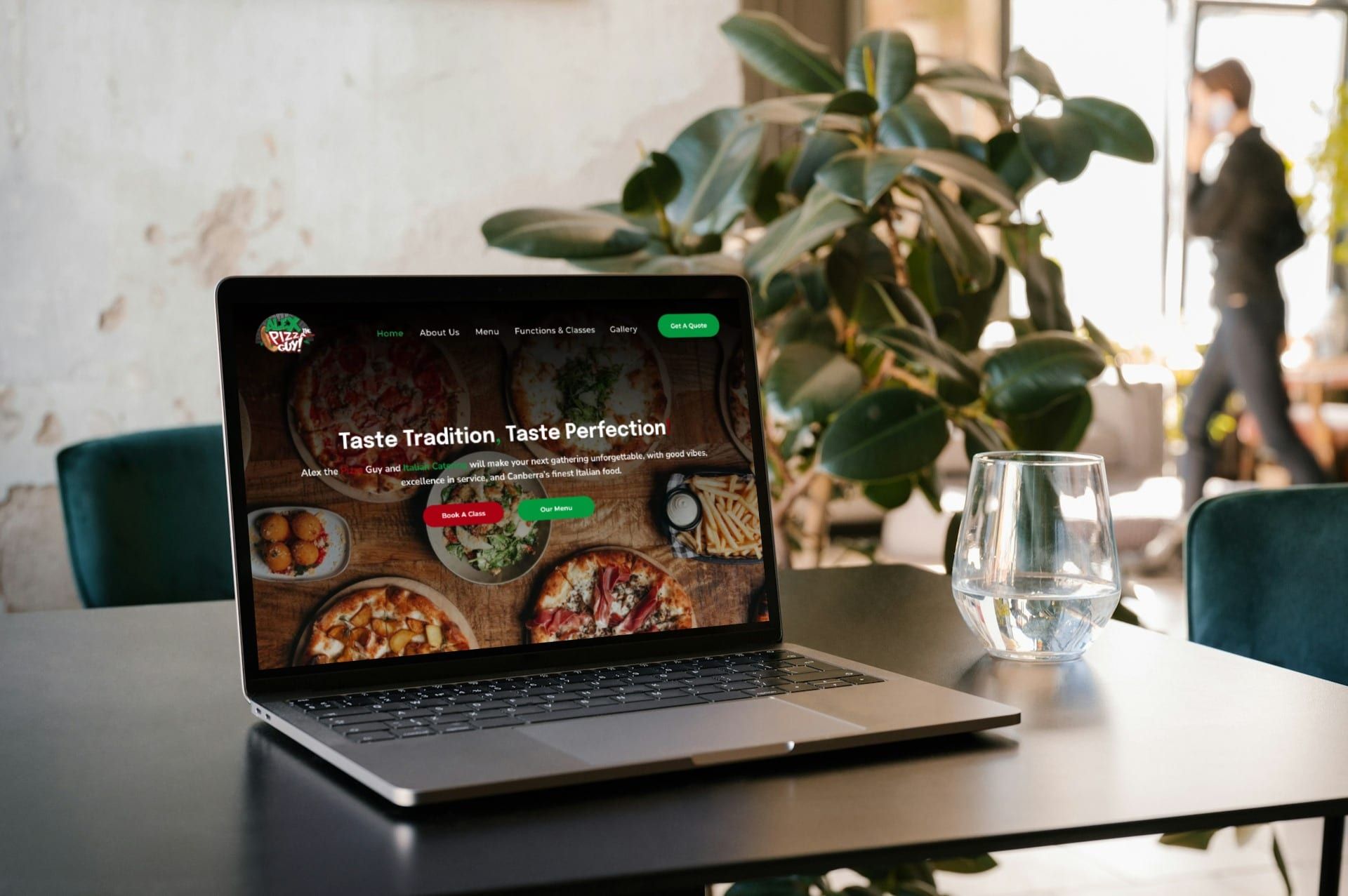 A laptop computer is sitting on a table with a plant in the background.