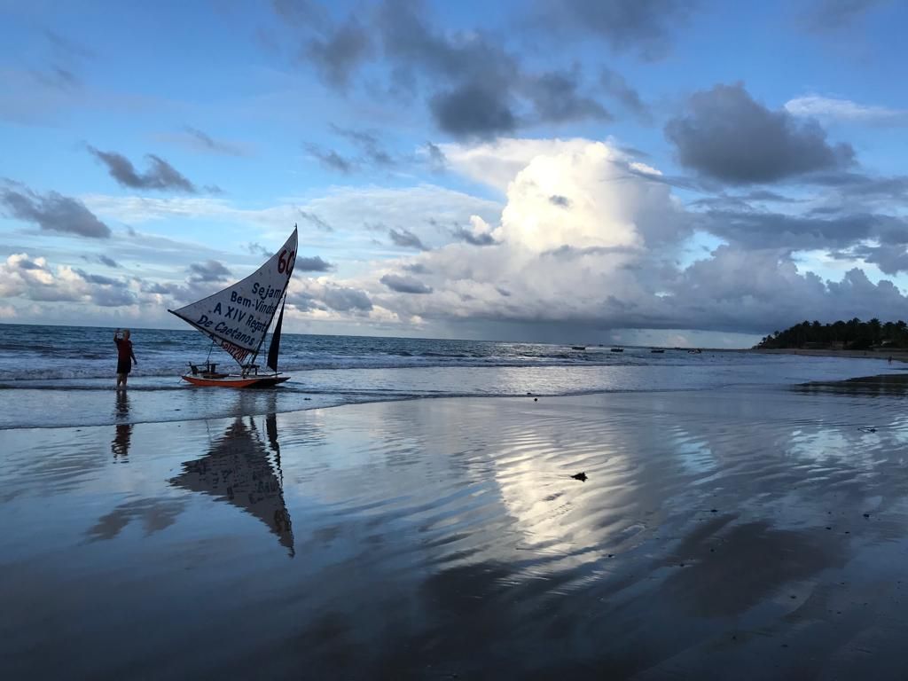 Um veleiro está flutuando no topo de uma praia arenosa.