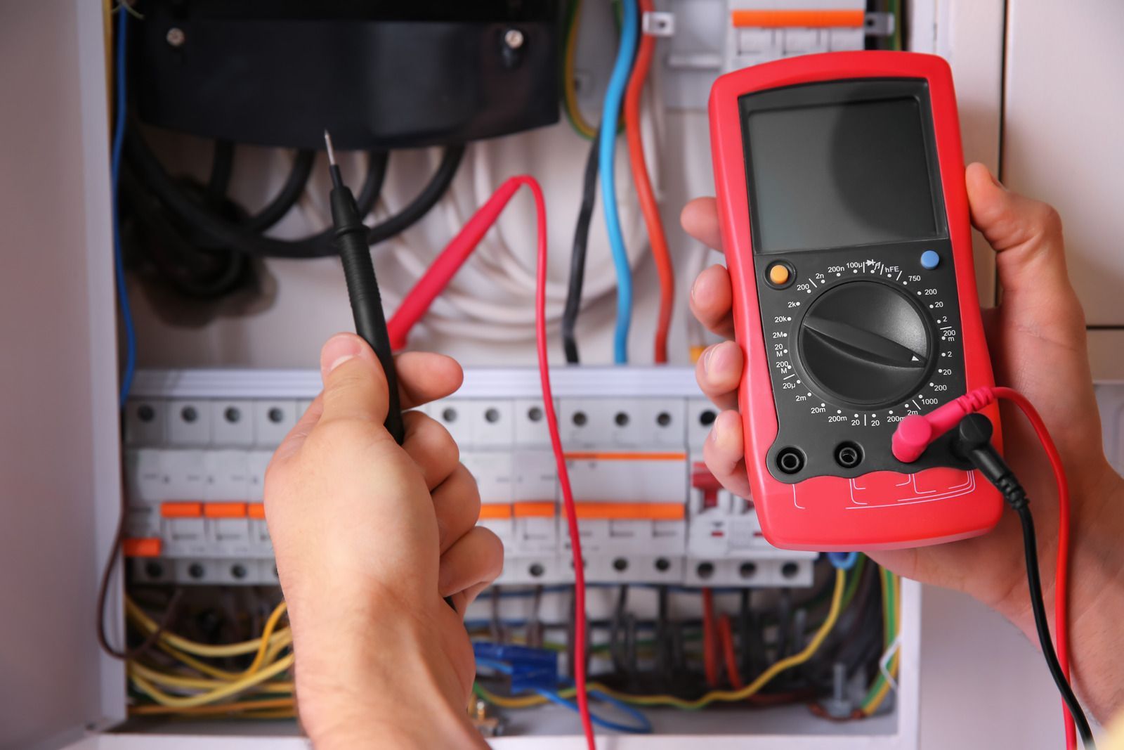 Person testing electrical panel with a multimeter.