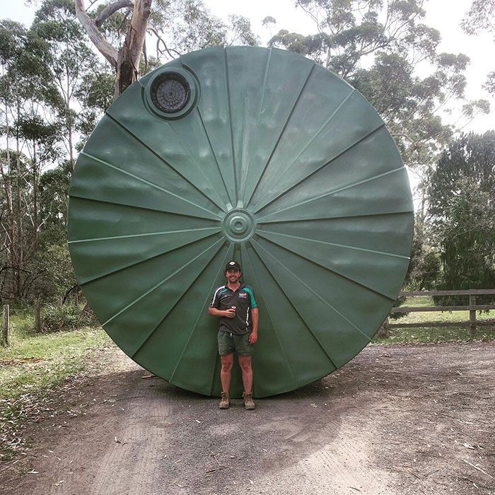 A Man Is Standing Next To A Large Green Circular Object — Bennett's Environmental In Kiama, NSW