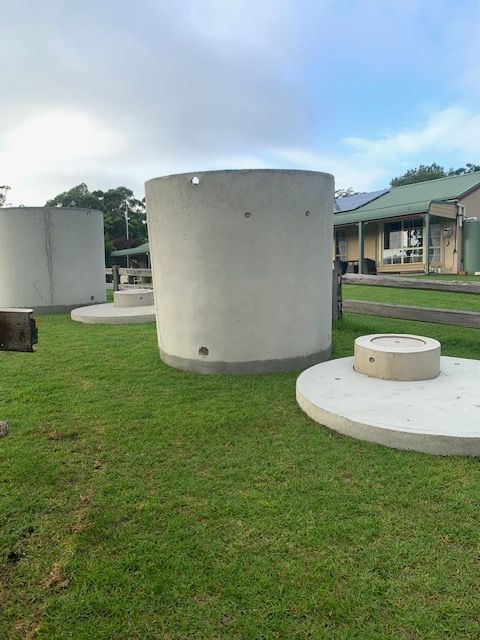 Large Concrete Water Tanks On Grass — Bennett's Environmental In Kiama, NSW