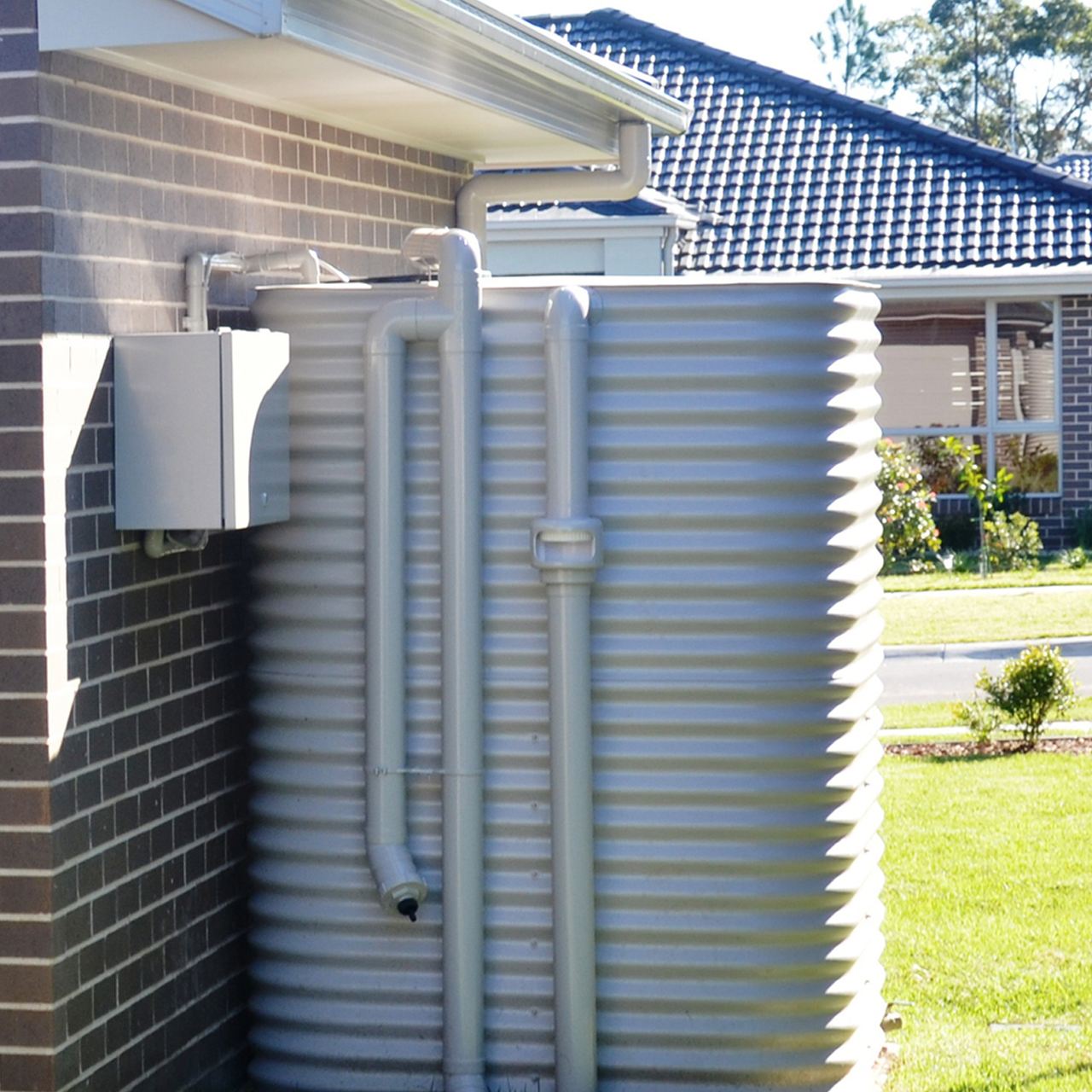 Two Gray Water Tanks Are Sitting Next To Each Other In Front Of A Building — Bennett's Environmental In South Nowra, NSW