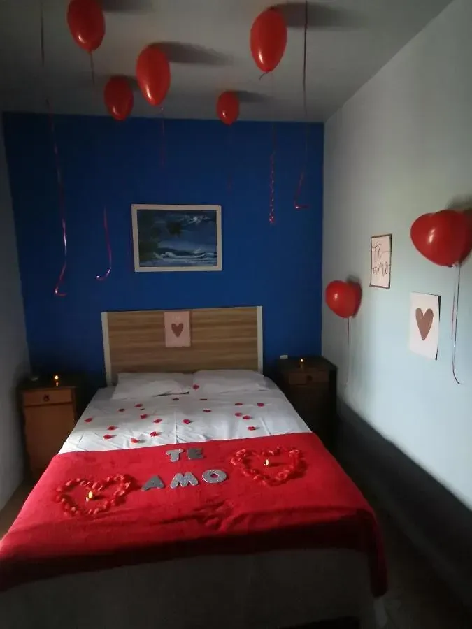Quarto pequeno decorado com balões vermelhos e motivos de coração para uma celebração romântica.