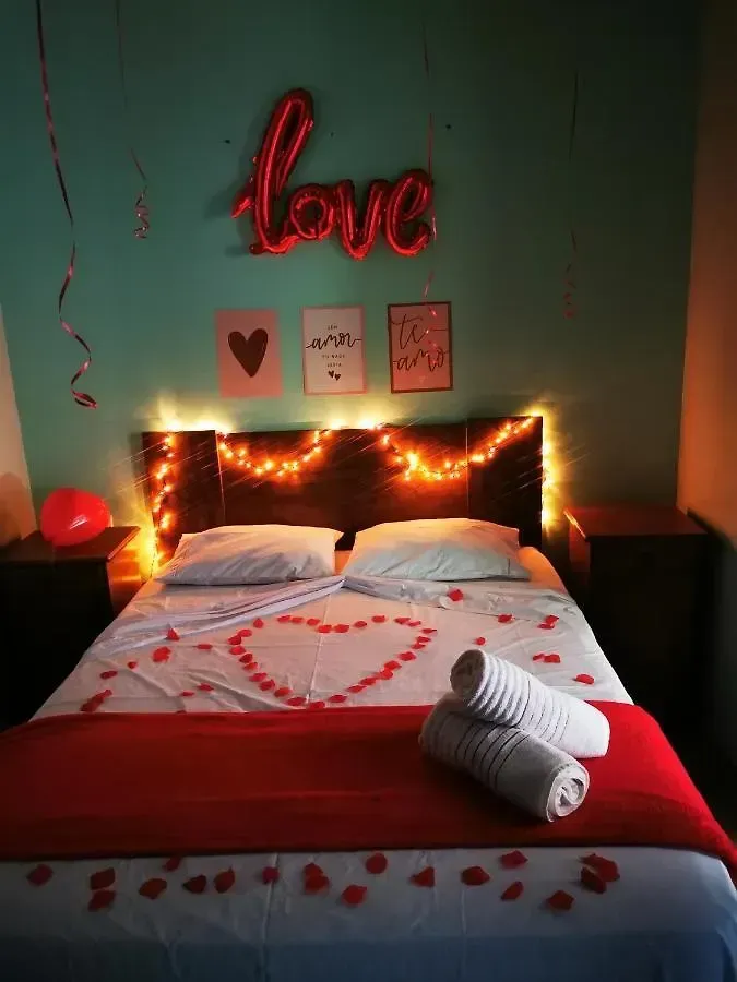 Quarto romântico com decoração em forma de coração, letreiro de neon vermelho com a palavra 