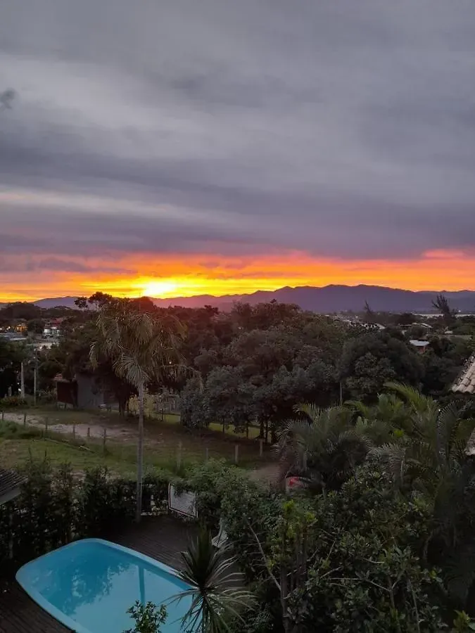 Pôr do sol sobre uma paisagem exuberante com uma piscina turquesa em primeiro plano.