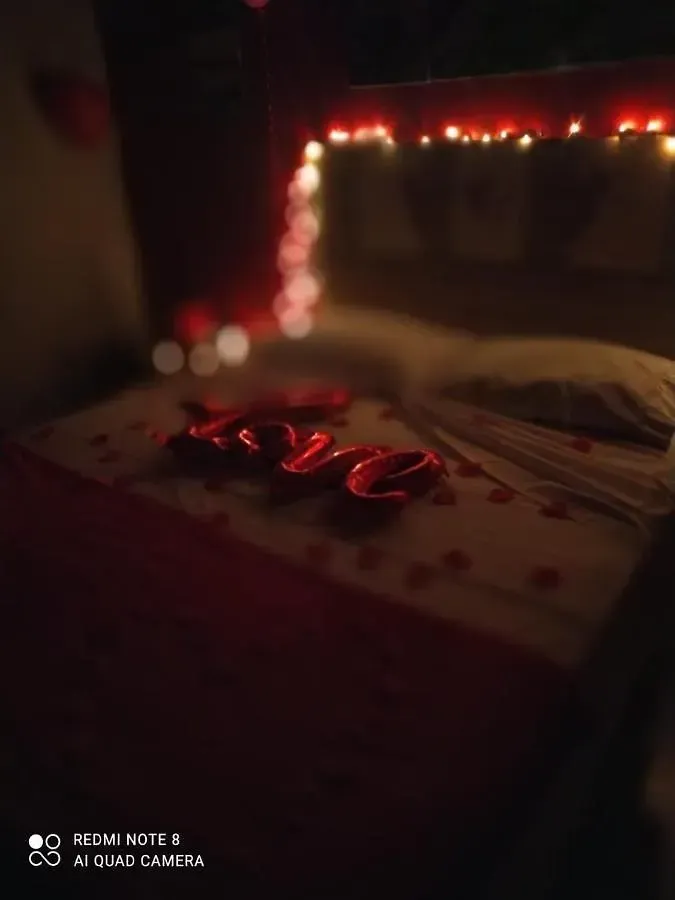 Quarto com pouca luz, um bolo decorado com letras vermelhas brilhantes formando a palavra 