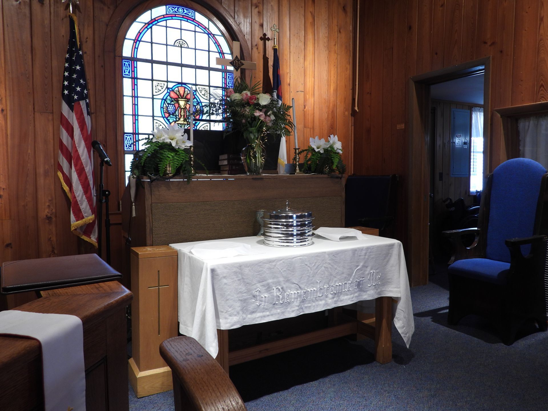 A church with a table and chairs in front of a stained glass window