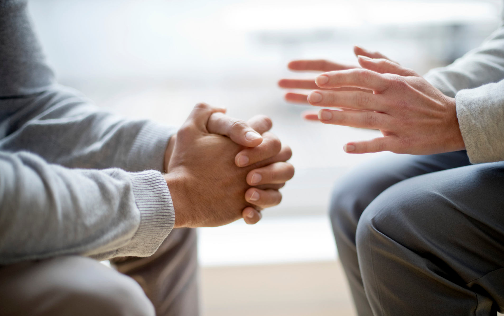 A man and a woman are sitting next to each other with their hands folded in prayer.