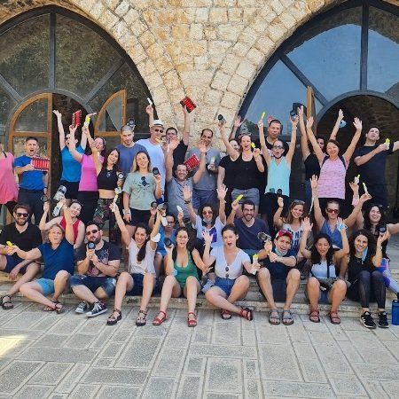 קבוצה גדולה של אנשים מצטלמים עם זרועותיהם באוויר
