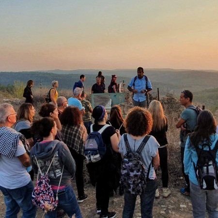 קבוצת אנשים עומדת על ראש גבעה עם תרמילים