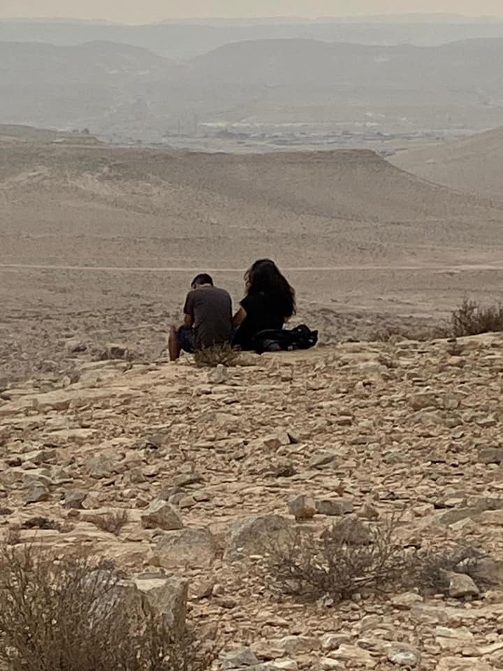 גבר ואישה יושבים על ראש גבעה סלעית במדבר.