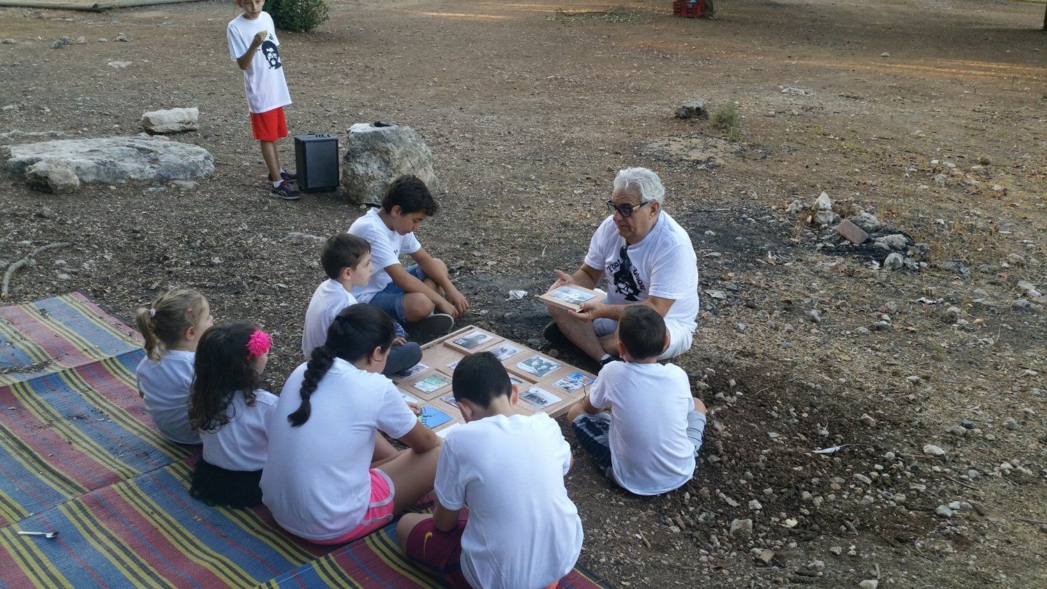 קבוצת ילדים יושבת סביב שולחן עם גבר מדבר איתם.