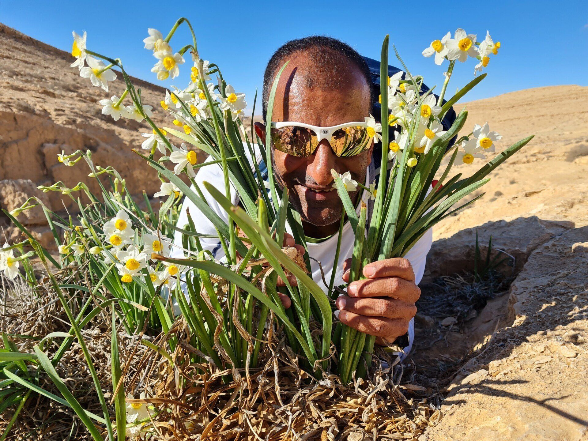 גבר המרכיב משקפי שמש מחזיק צרור פרחים מול פניו.