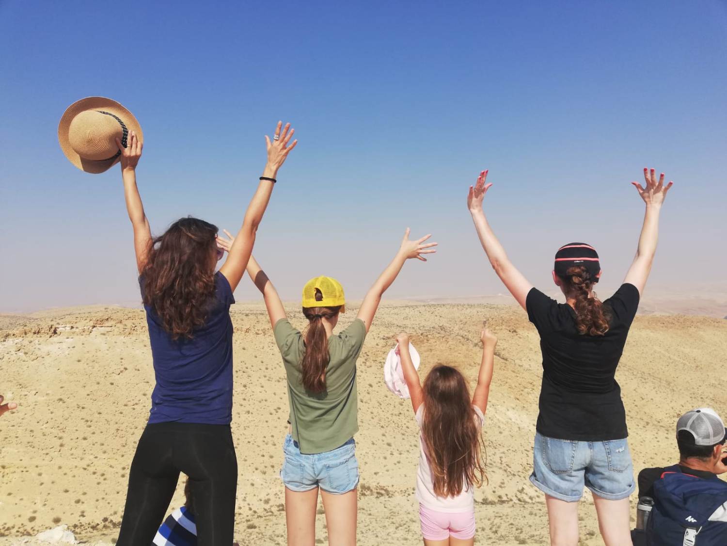 קבוצת אנשים עומדת במדבר עם זרועותיהם באוויר