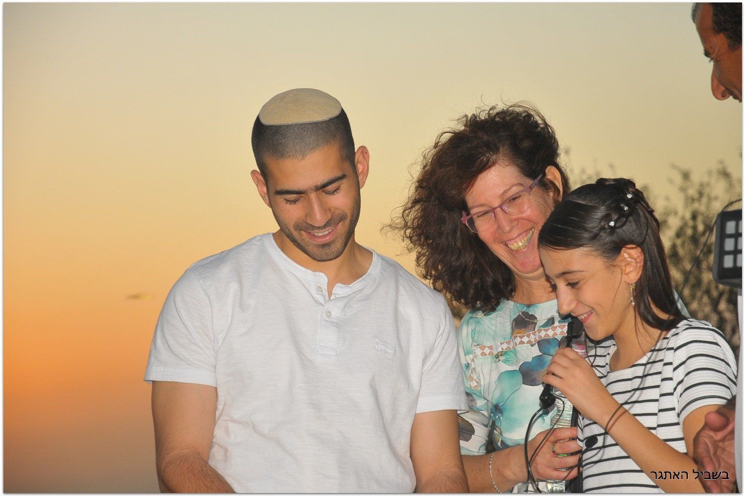 גבר ואישה עומדים ליד ילדה אוחזים במיקרופון.